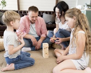 parents, their son, and their daughter sitting on the floor, playing Jenga