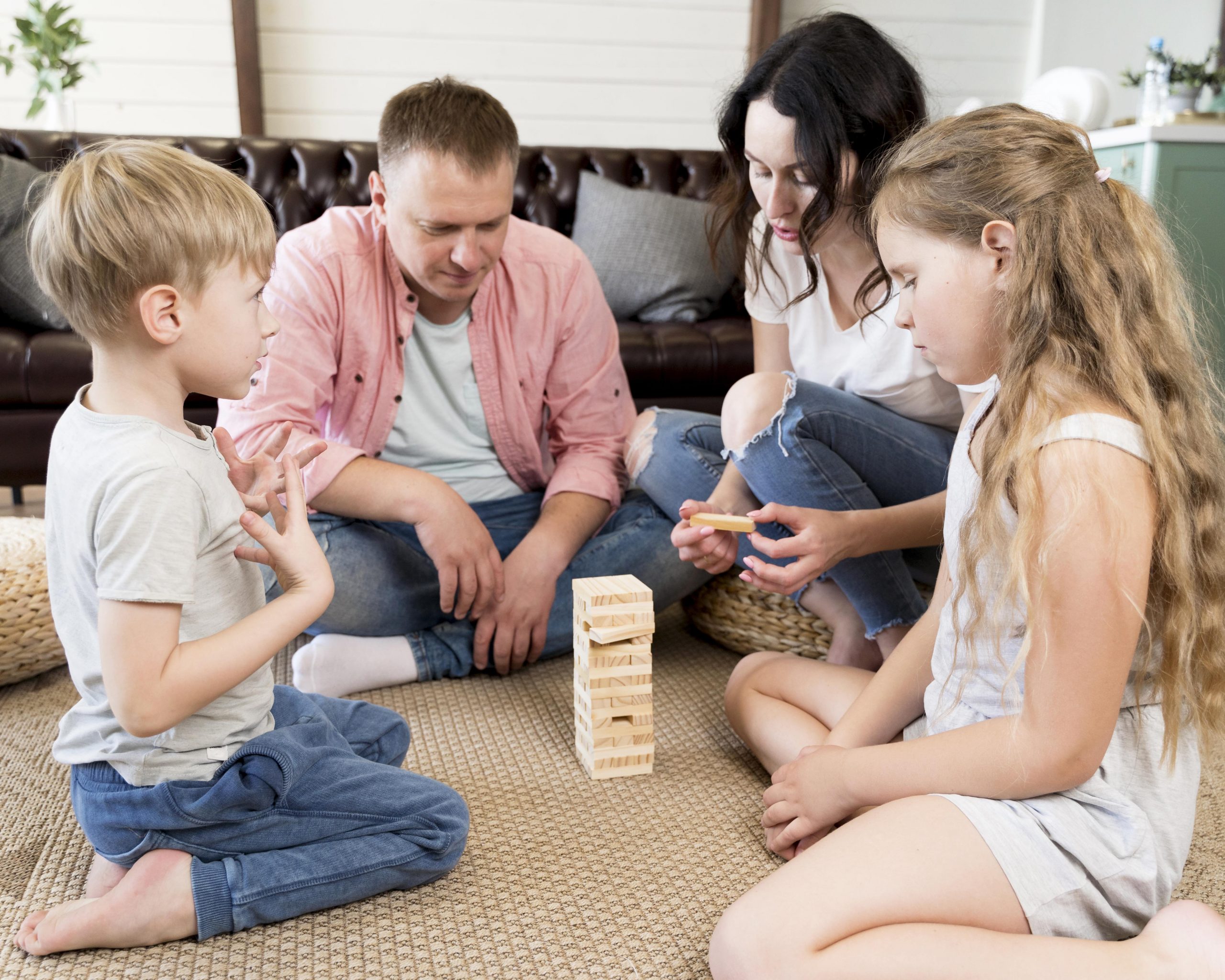 parents, their son, and their daughter sitting on the floor, playing Jenga