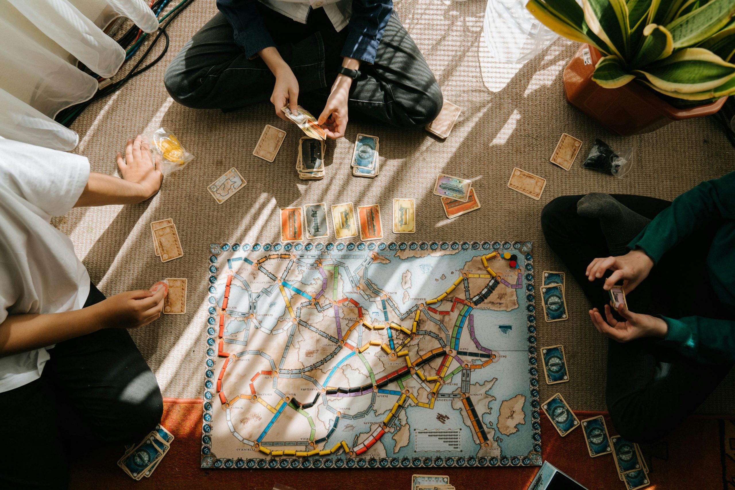 three people sitting on the floor playing Ticket to Ride