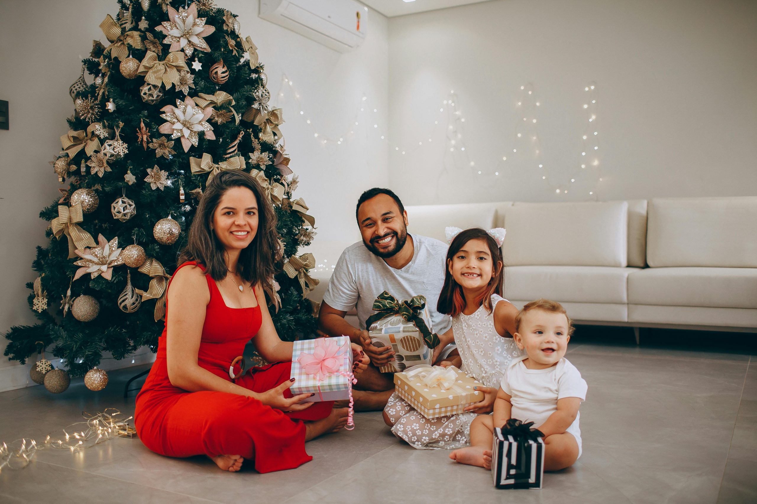 family sitting together on the floor of a cozy living room, surrounded by Christmas decorations