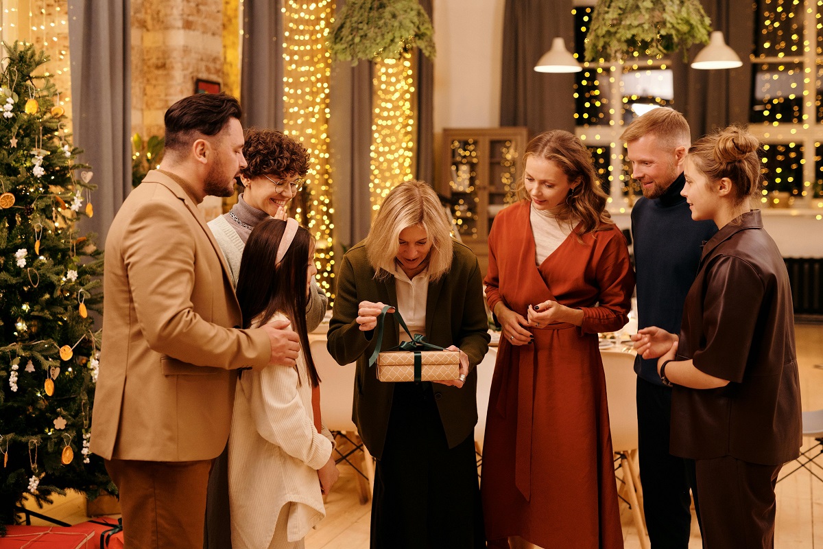 woman opening a Christmas present as her family members watch