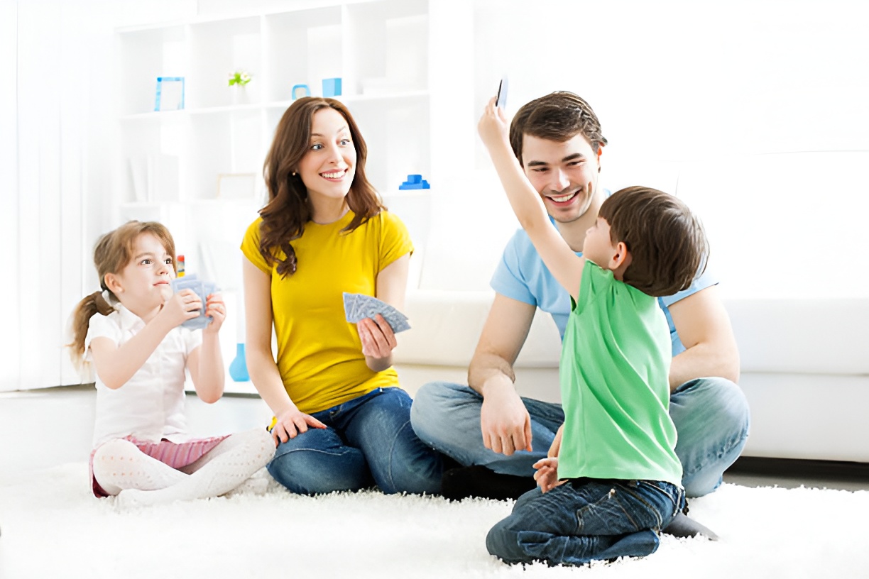 mom, dad, and two kids playing a card game in the living room